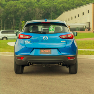 A blue Mazda parks in a lot.