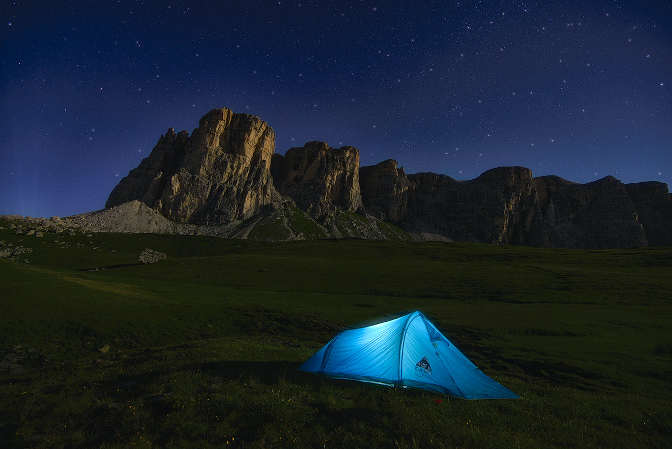 A tent set up at night before mountians