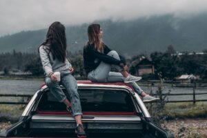 Two girls sitting on top of a car