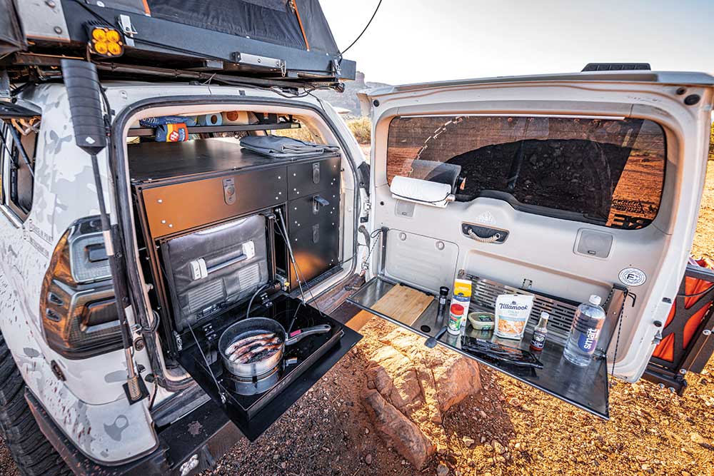 The open rear door of the GX470 reveals a custom storage and cooking setup.