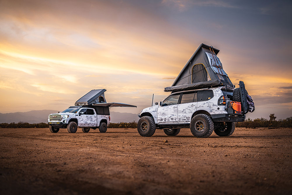 The GX470 and a similarly painted truck, both with roof top tents deployed, park on dirt.