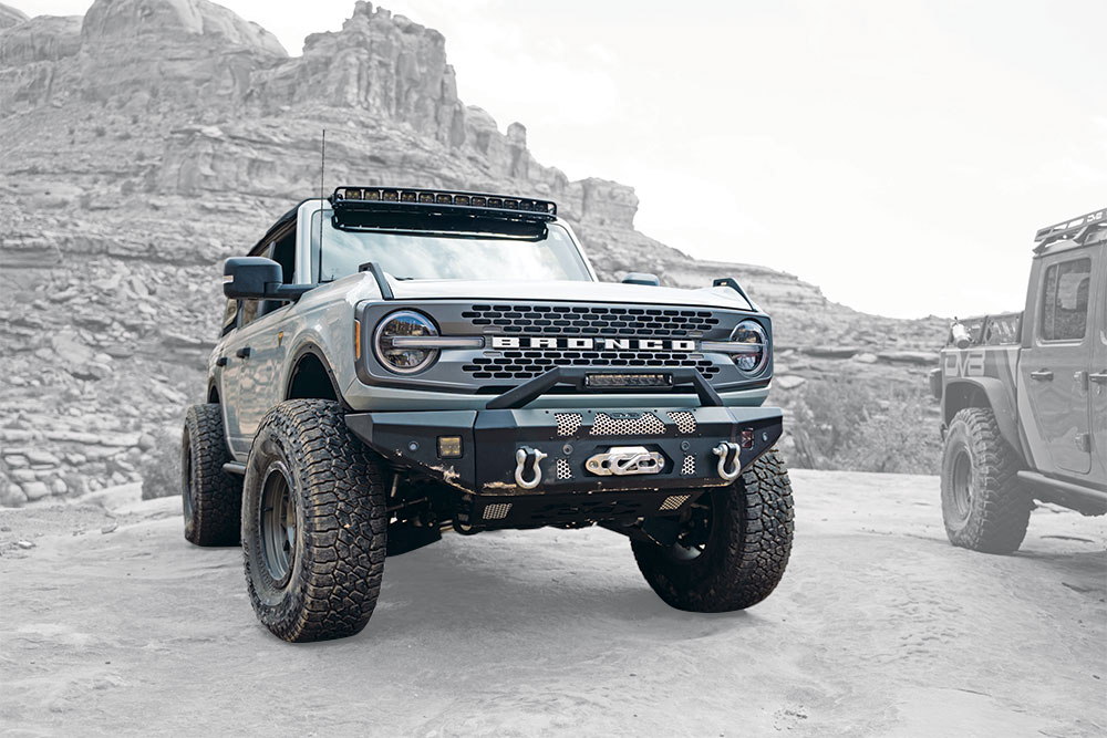 A Bronco bug out rig parks on a desert cliff with an added metal bumper.