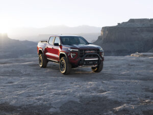 The red GMC Canyon truck parks in front of a scenic rocky view.