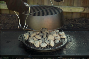 A cast iron grill heating up coals for cooking.