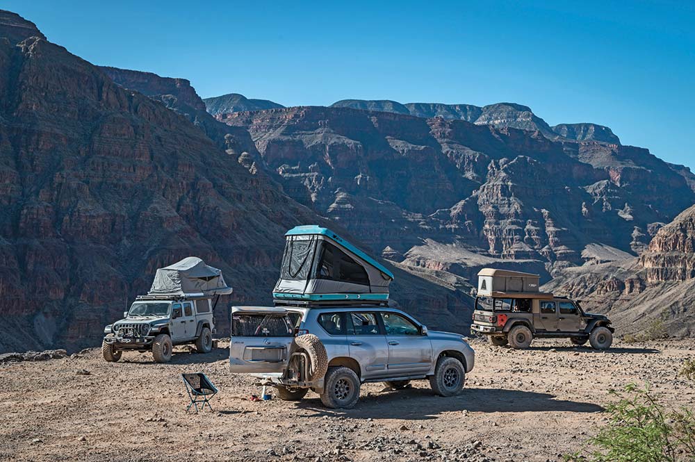 A Lexus GX460 camped among two Jeep concept vehicles, all three with roof top tents, at a Grand Canyon campsite.