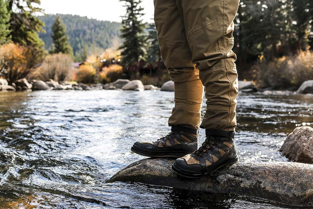 a person in boots standing in a river