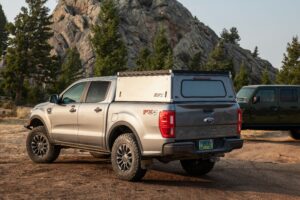 A gray Ford F-150 overlanding with a truck topper.