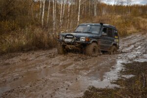 An overlanding Land Crusier heads through a muddy puddle.