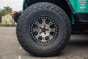 Back off-road tire on a teal vehicle.