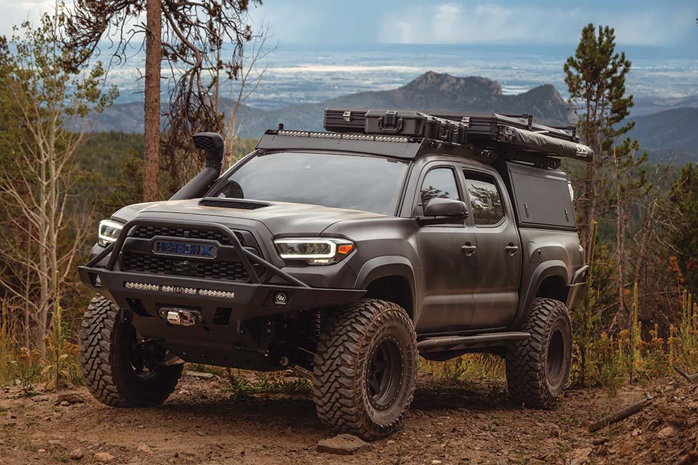 Parked on the trail, the HerschX Tacoma stands on large wheels and is outfitted with gear on all sides.