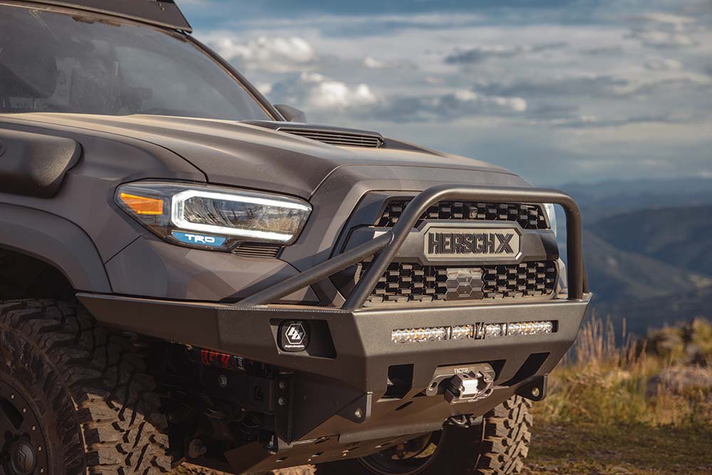The front grile features a lagre bull bar, HerschX Tacoma branding, and a winch.