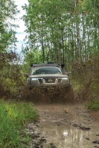 Nissan Frontier drives through a muddy road. 