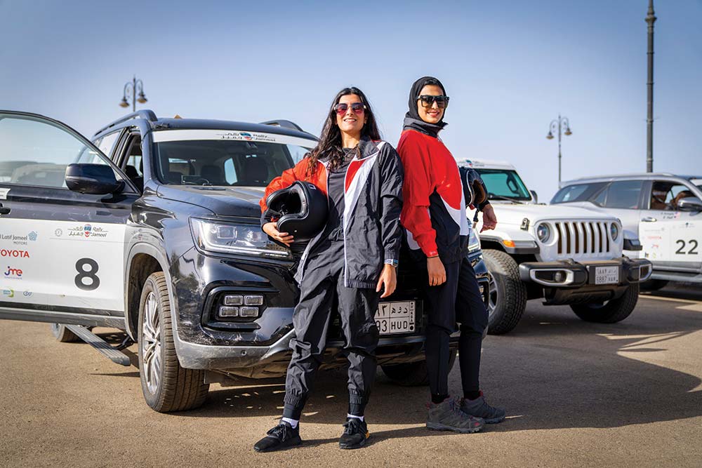 Female drivers pose in front of their car
