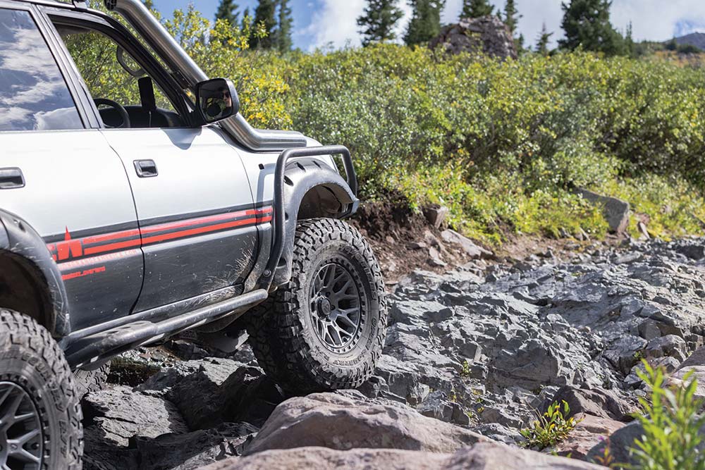 Gray rock formations form a path through ground cover as the Land Cruiser drives uphill.