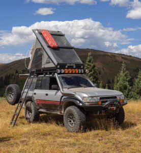 The Land Cruiser parked on a grass field with roof top tent deployed.