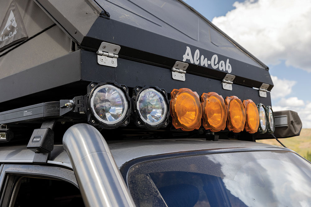 Up front above the windshield is a KC lightbar and Alu-Cab roof top tent.