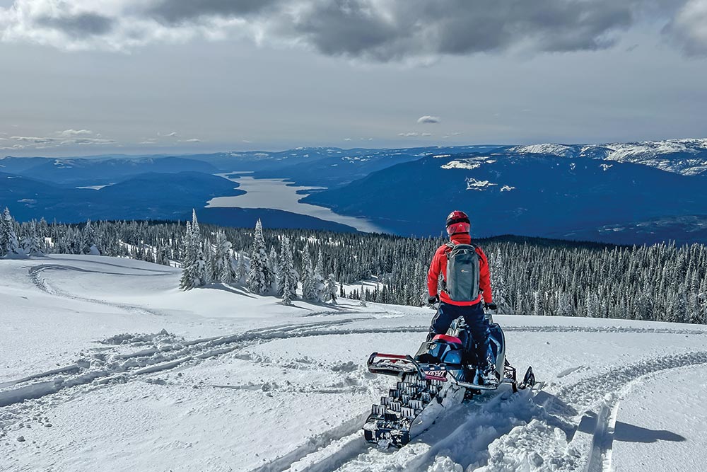 Winter off-road rider looks out over a mountain vista. 