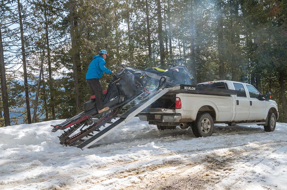 Snow mobile gets backed off a pick up truck 