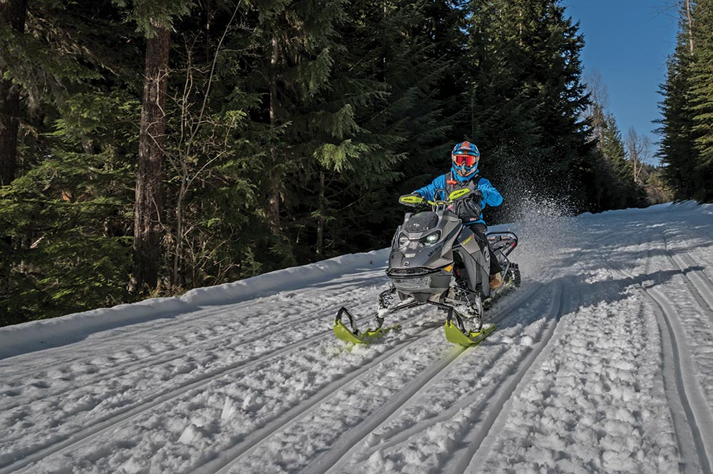 Rider drives a ski-doo down a snowy road 