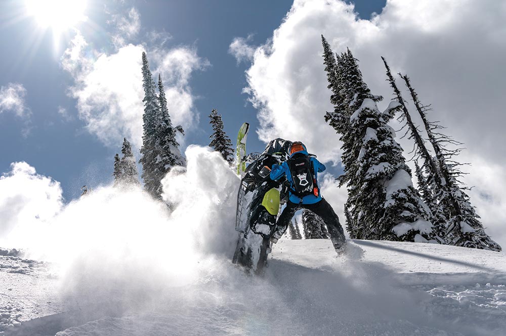 A rider on a snowmobile kicks up powder