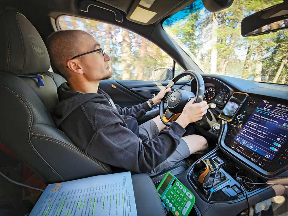 A blad man with glasses sits in the drivers seat of the Subaru sponsored Alcan rally car.