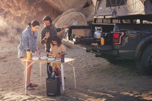 A family sets up their camp kitchen off the back of their truck.