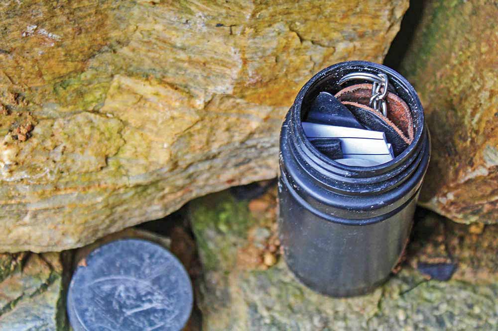 Once the top is opened, it is revealed that the small black canister is jam packed with small trinkets and papers.