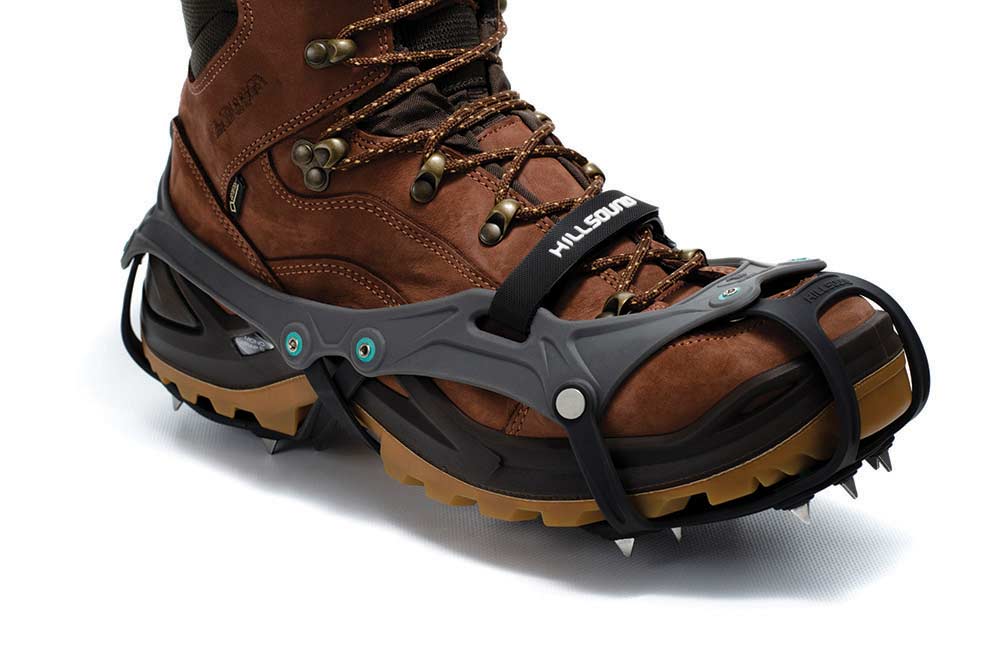 A brown boot on a white background with the gray and black rubber crampon attached.