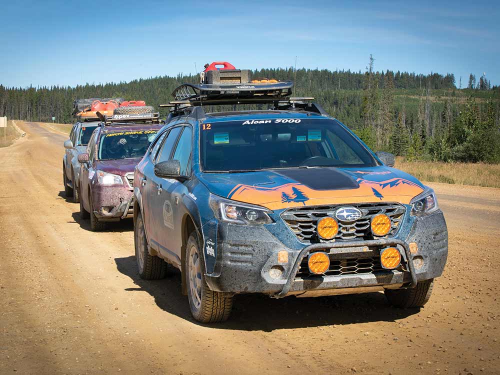 The Subaru Outback Wilderness with orange badging leads a pack of 3 cars at the Alcan 5000 rally.