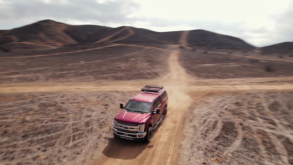 From above, the red F250 kicks up dust with its Nexen Roadian ATX tire set.