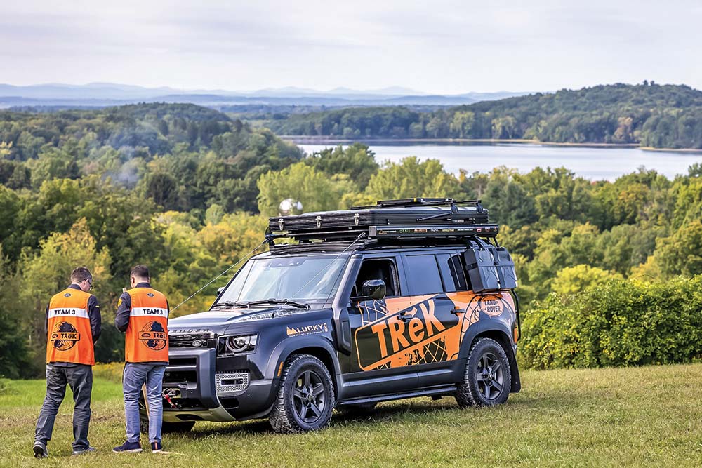 Two comeptitors park their Land Rover TReK Defender on a grass field overlooking a river in upstate New York.