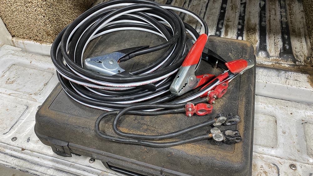 On top of a well-loved back box containing the author's welding kit are two connector leads and a long jumper cable.