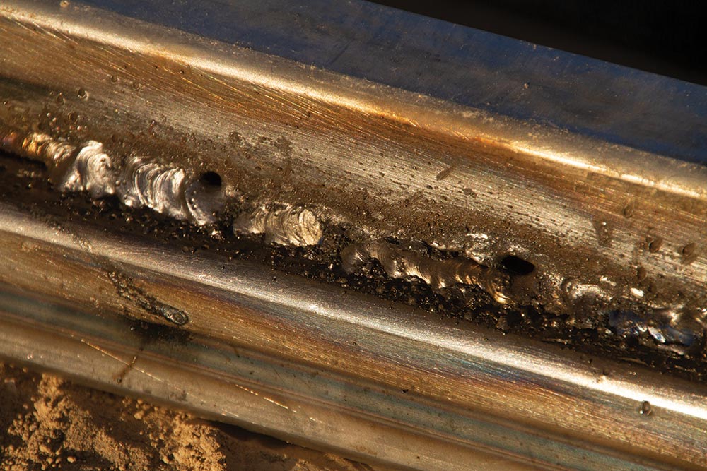 An close up improper weld uneven and marked with burns and holes.