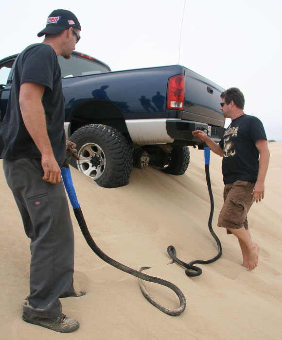 Recovery gear being used in sand dunes on blue truck