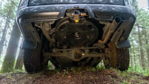 The underbody of an SUV driving through the woods.