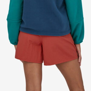 The back and legs of a gal in a blue sweatshirt and red shorts.