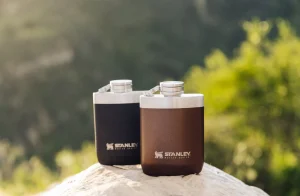 A black and brown flask sit on a rock.