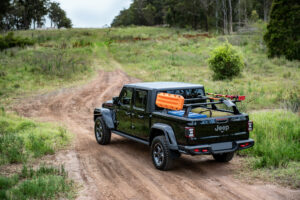 A black Jeep Gladiator with Rhino Rack Reconn-Deck bars mounted across the bed.