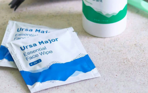 The white and blue face wipe packets rest on a cream counter top.