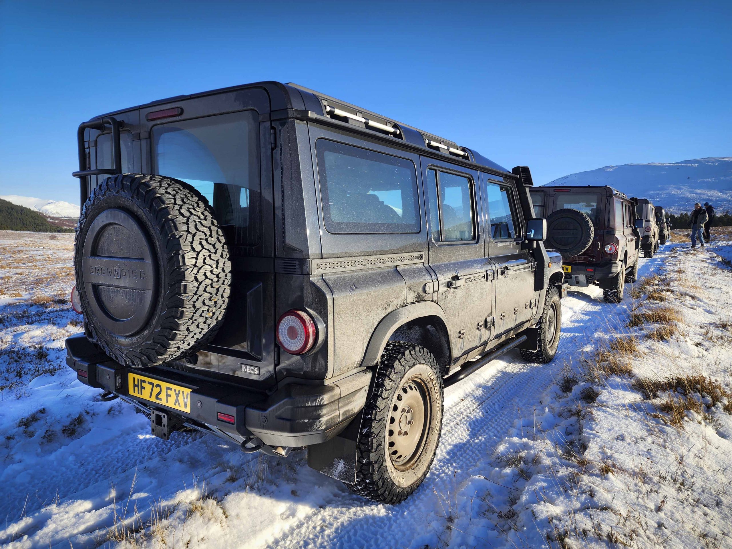 A rear view of four SUVs parked on a snowy trail.