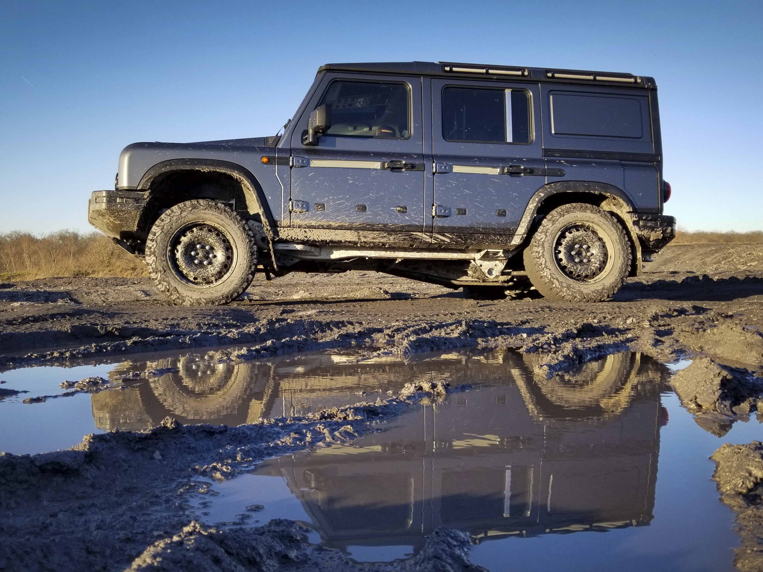 A prototype INEOS Grenadier is parked next to a mud puddle.