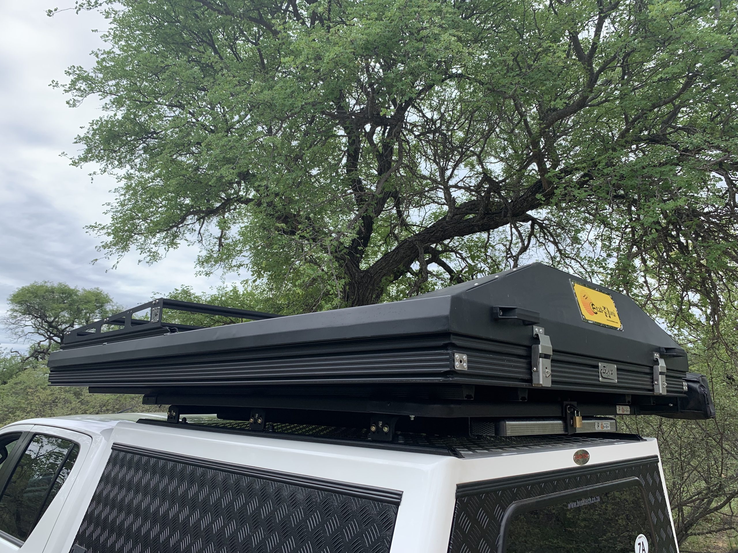 The black hardshell Blade RTT mounted on top of a white truck. 