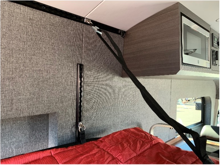 Inside of a van showing strap attached to track mounted high near ceiling.