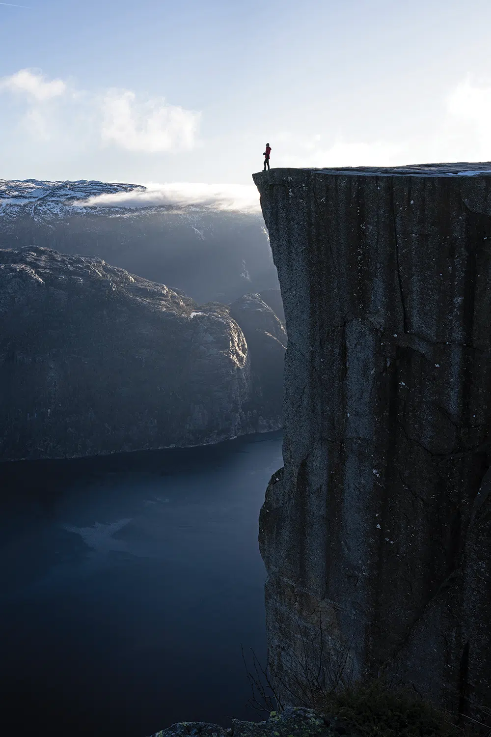 Lisa feels miniaturized on a stupendous-sized rock at Preikestolen