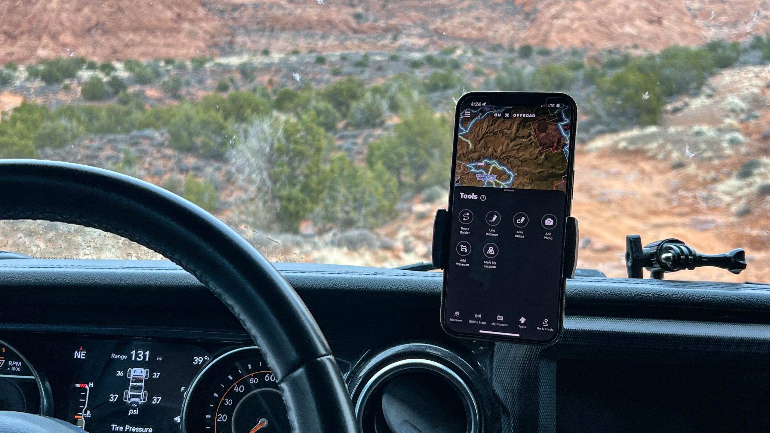 Phone mounted to a car dashboard displays the OnX Route Builder app.