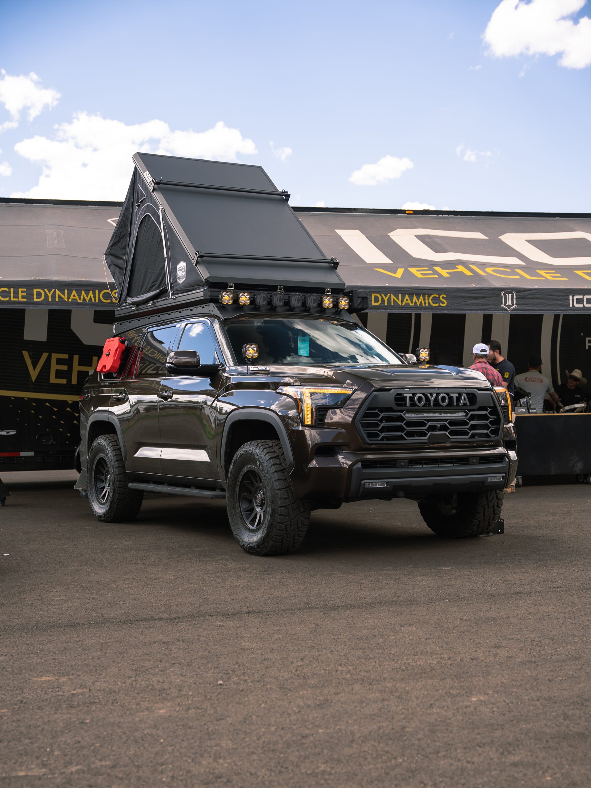 A shiny black 4Runner with pop up tent on top at the Expo West Icon Vehicle Dynamics tent.