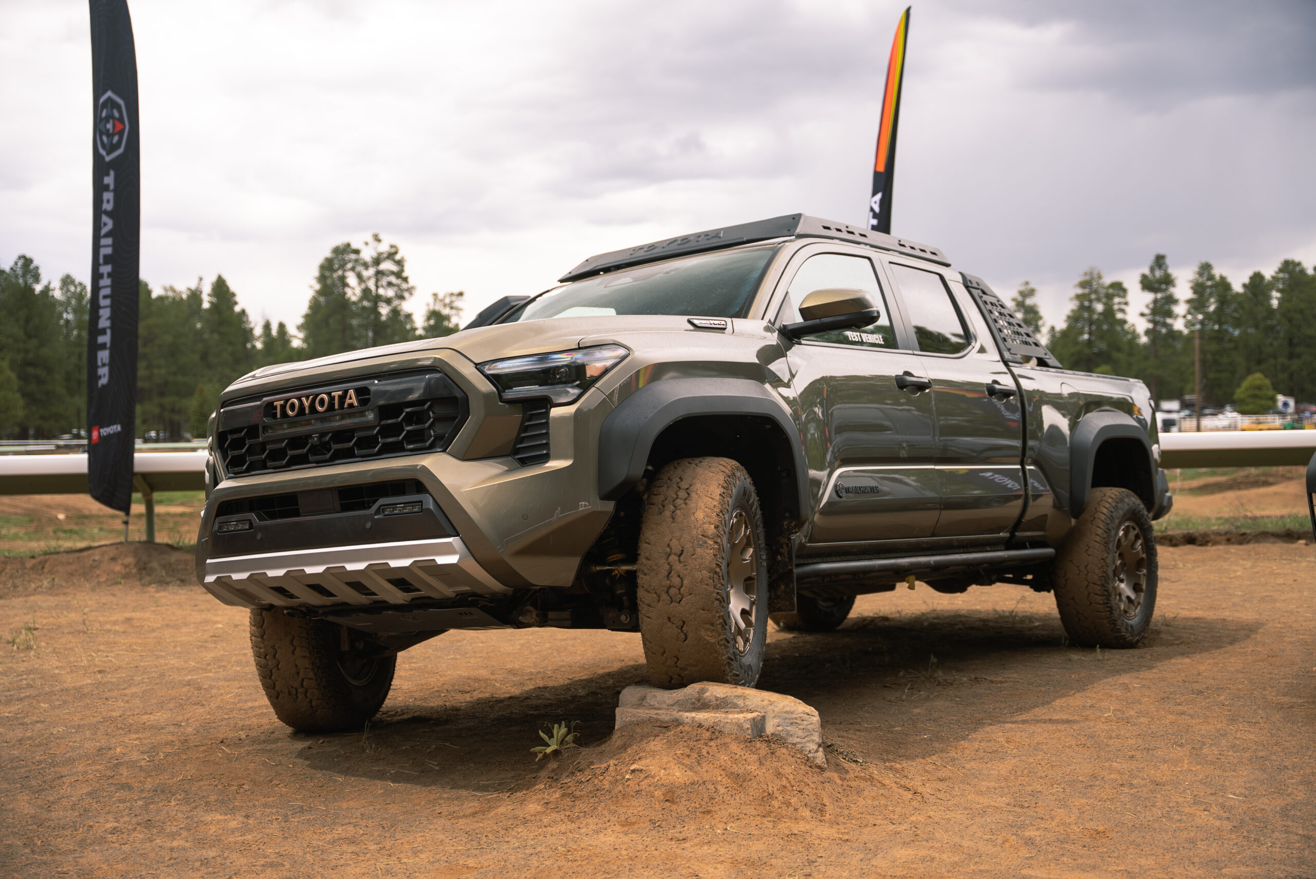 A gray-green 2024 Tacoma Trailhunter pops a front tire on a rock.