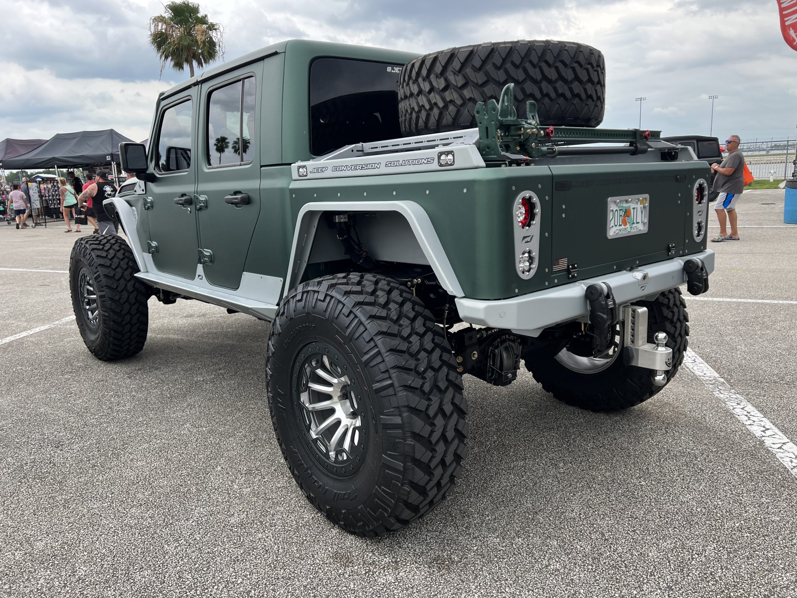 Green Jeep Gladiator with spare tire mounted in bed.