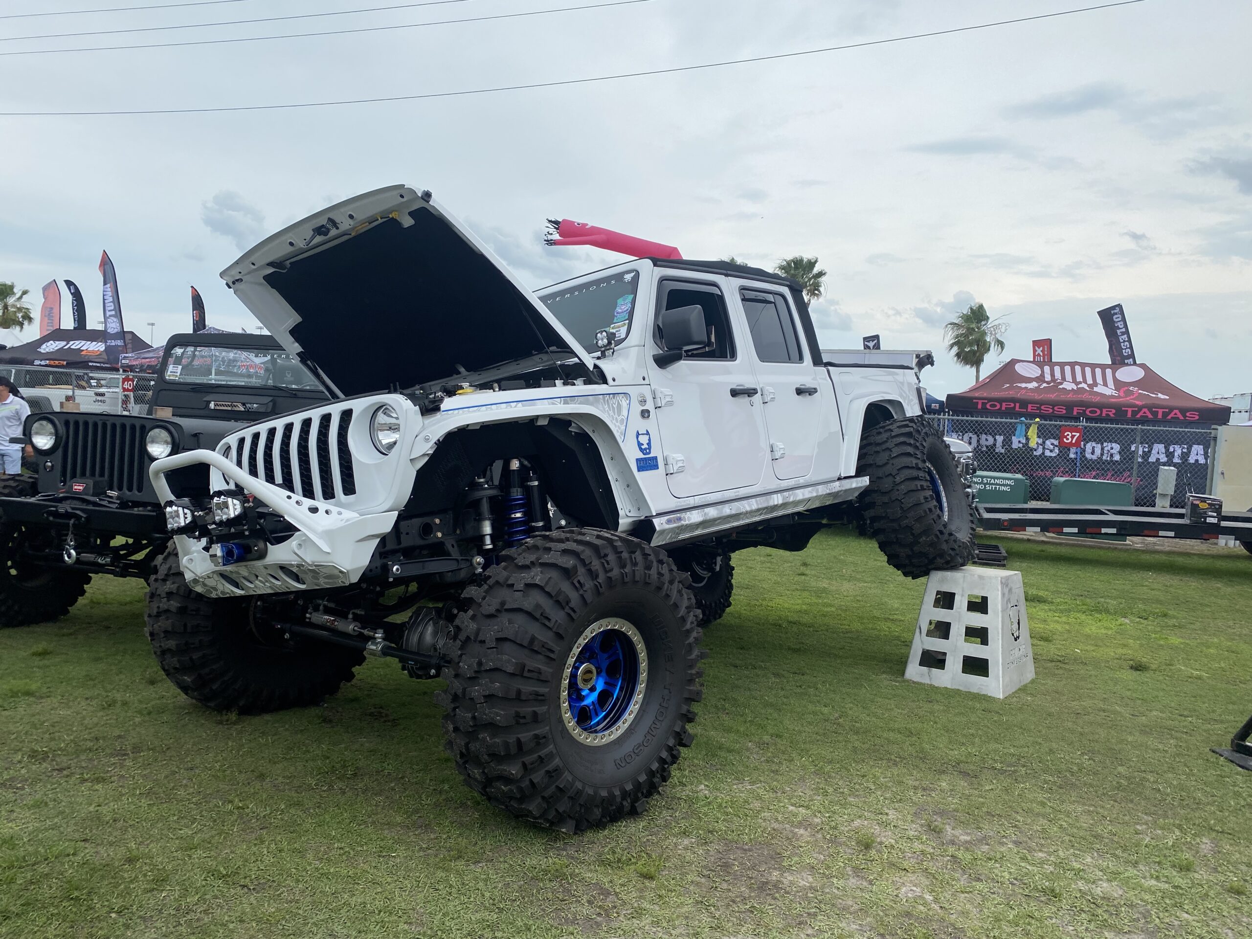 White Jeep Gladiator with rear tire raised to flex.