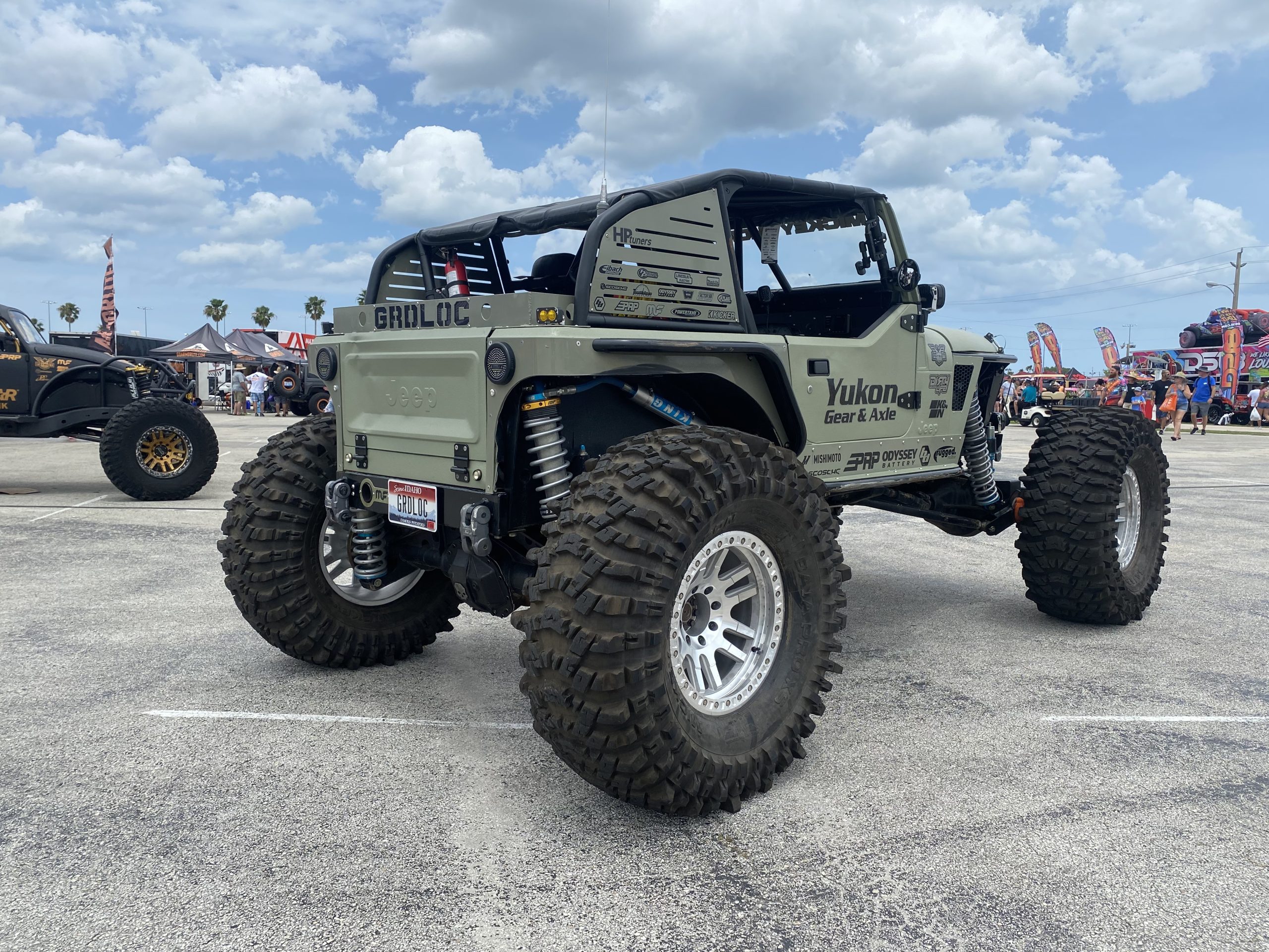 Green Jeep parked on asphalt with top off.